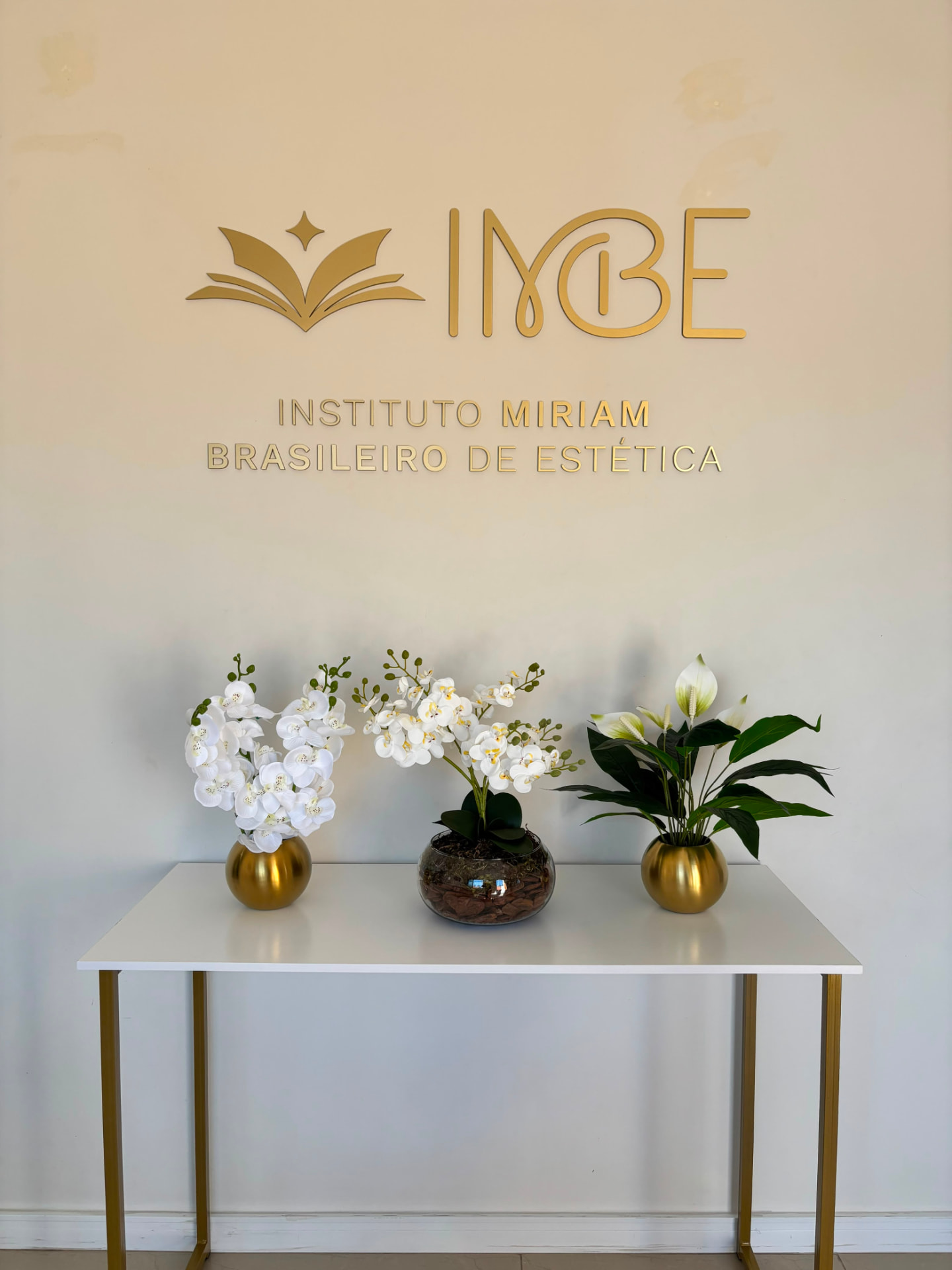 Logo IMBE na parede com decoração de flores